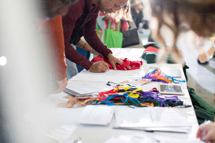 People arriving and receiving identification card at conference registration table